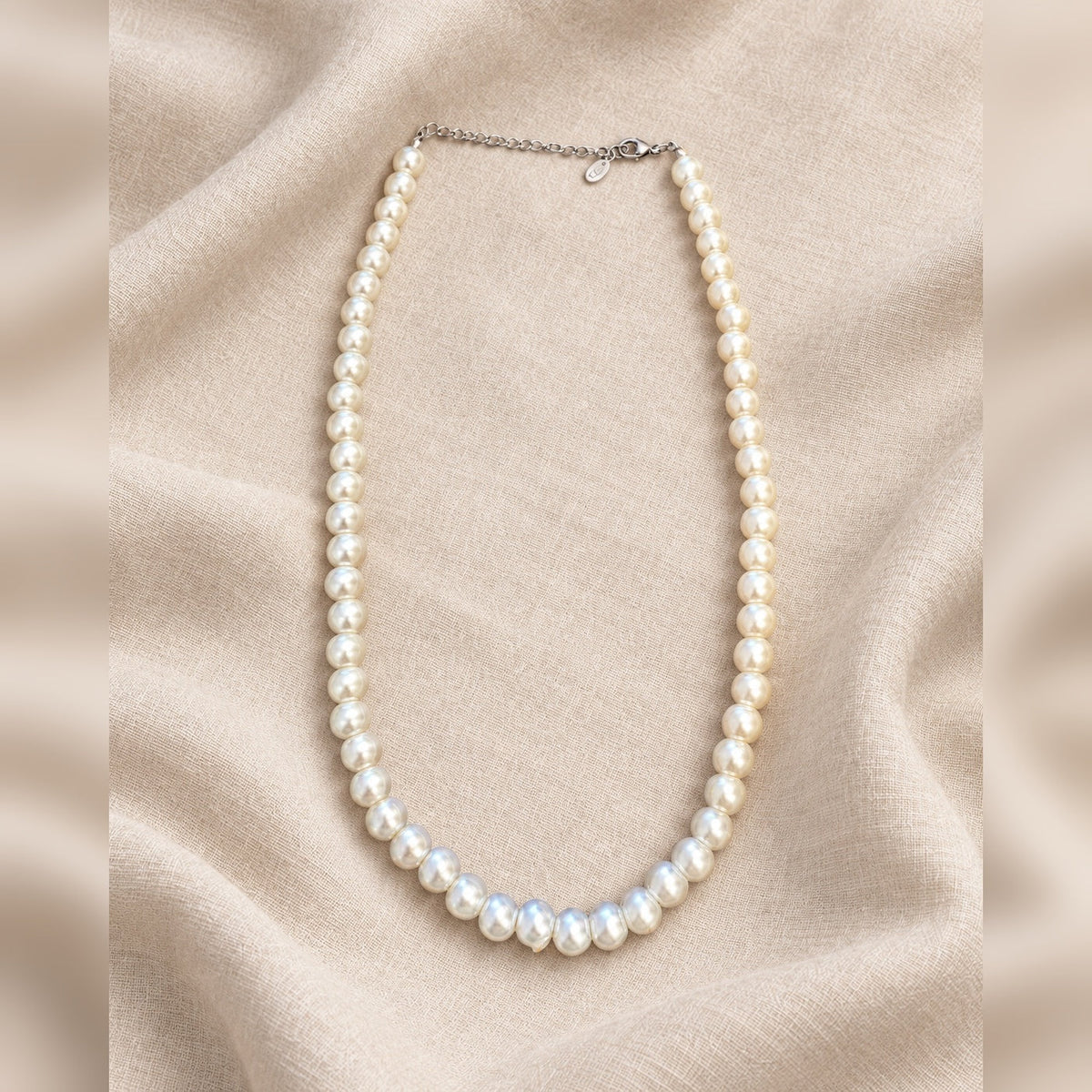 Collar efecto perla blanca sobre tejido marfil, formato cuadrado