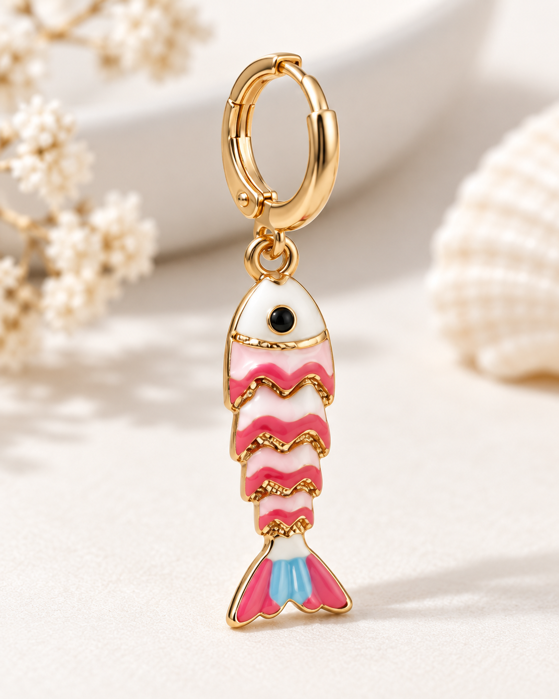 Detalle profesional de pendiente de pez esmaltado rosa con aro dorado