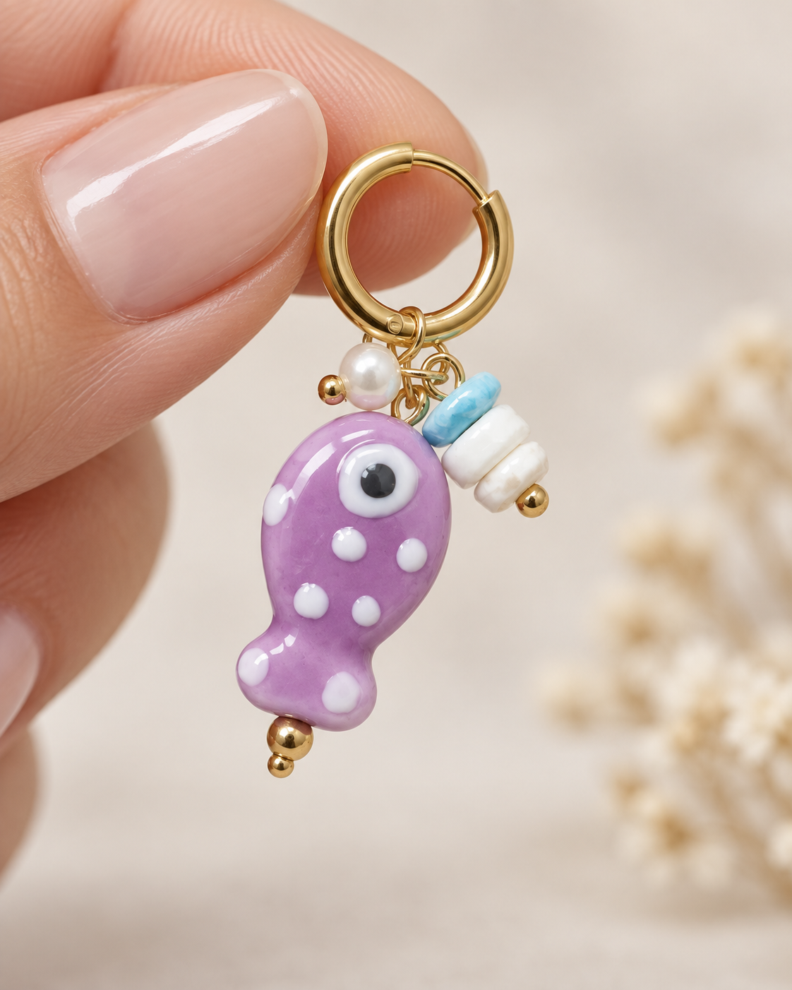 Pendiente dorado individual con pez lavanda y cuentas decorativas