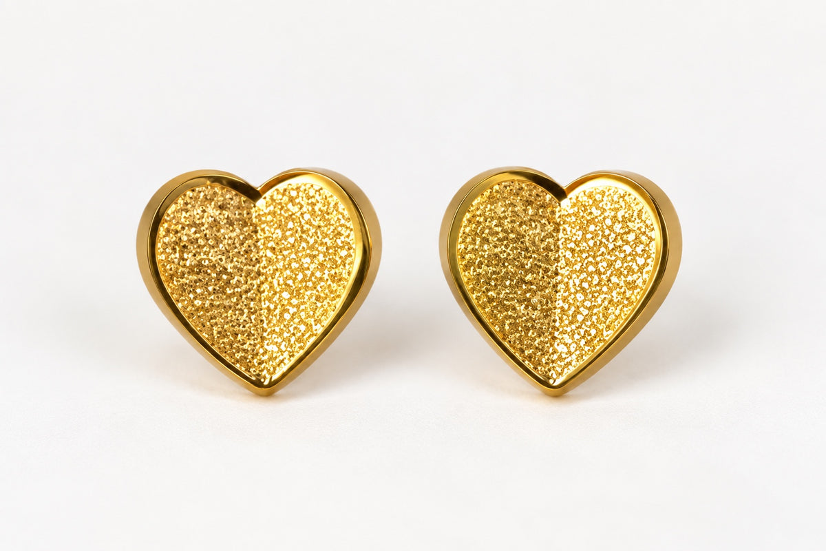Dos pendientes de corazón dorados sobre fondo blanco