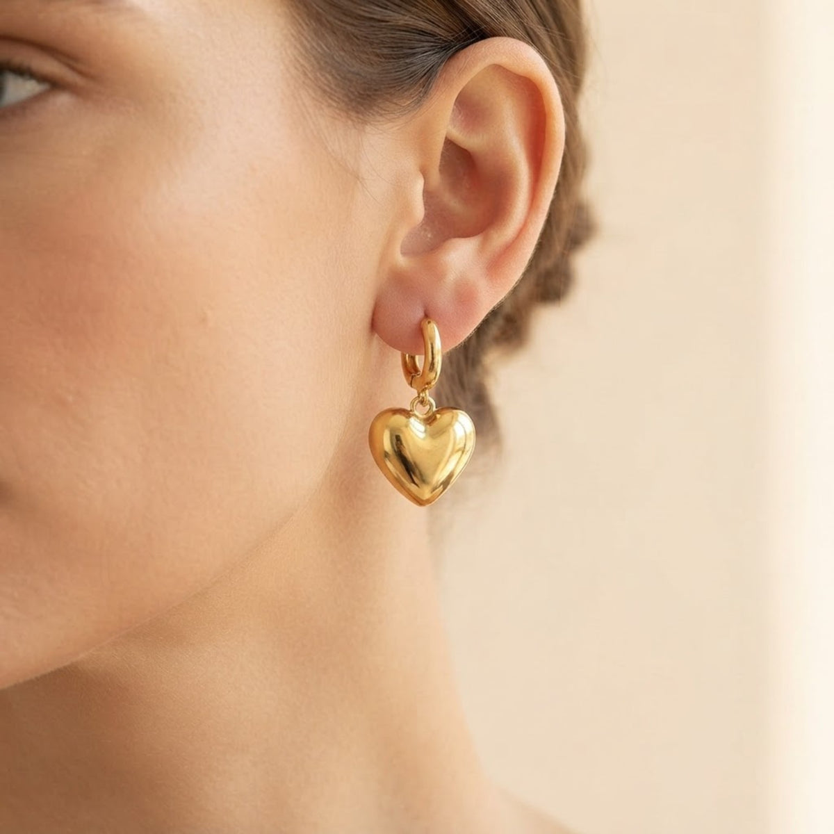 Pendiente de aro dorado con corazón puesto en la oreja