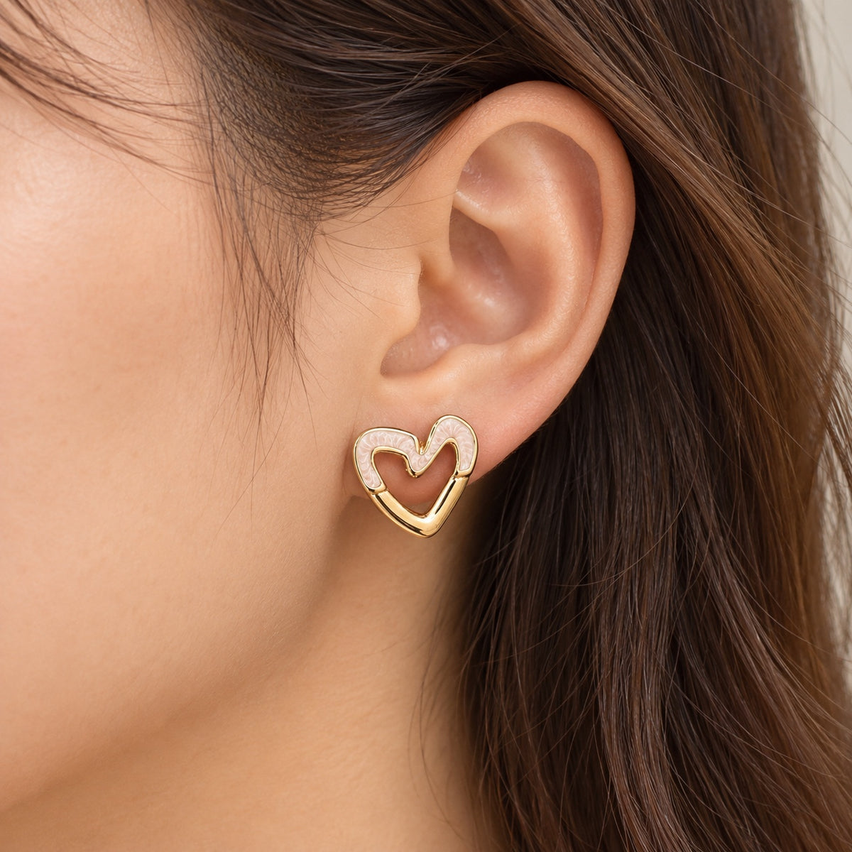 Pendiente corazón dorado y rosa llevado en la oreja