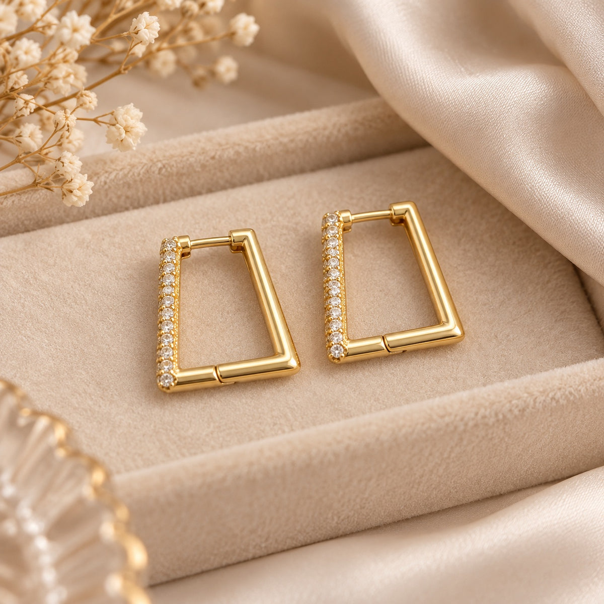 Pendientes geométricos dorados sobre fondo beige