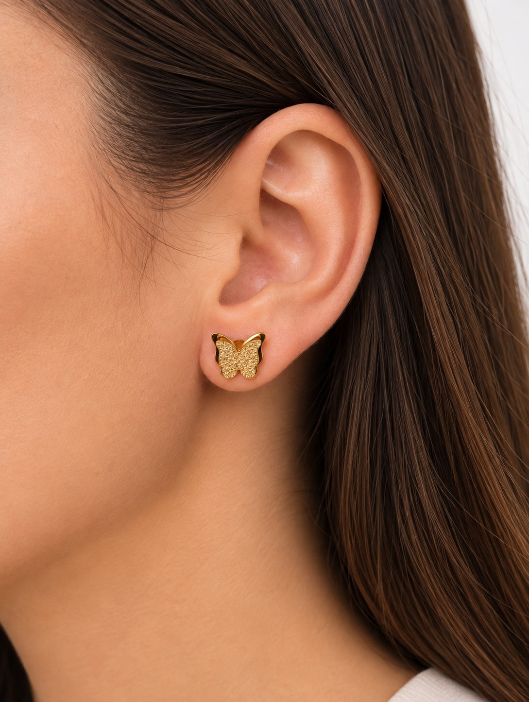 Modelo con pendientes de mariposa dorados