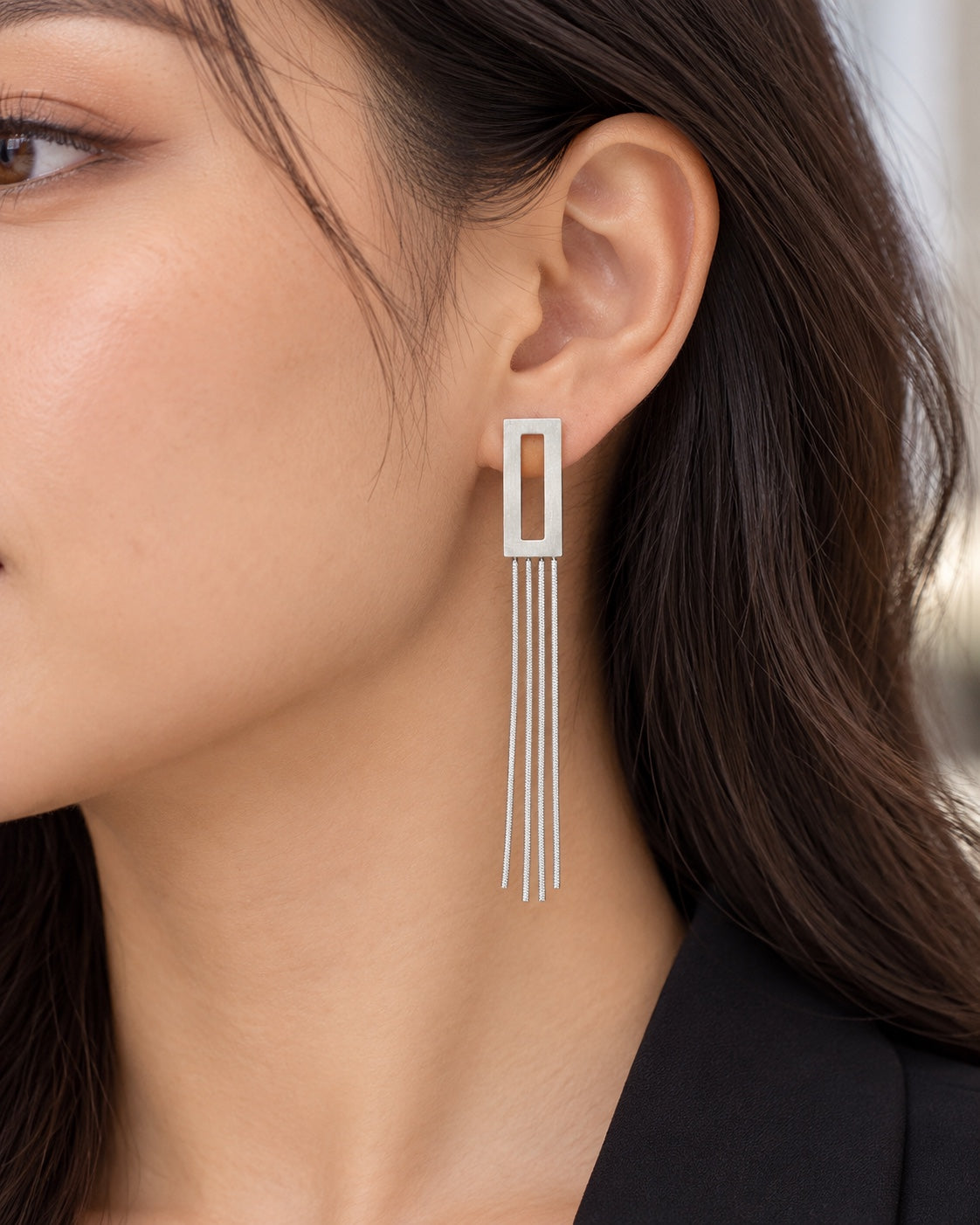 Pendiente rectangular plateado con cuatro cadenas colocado en la oreja