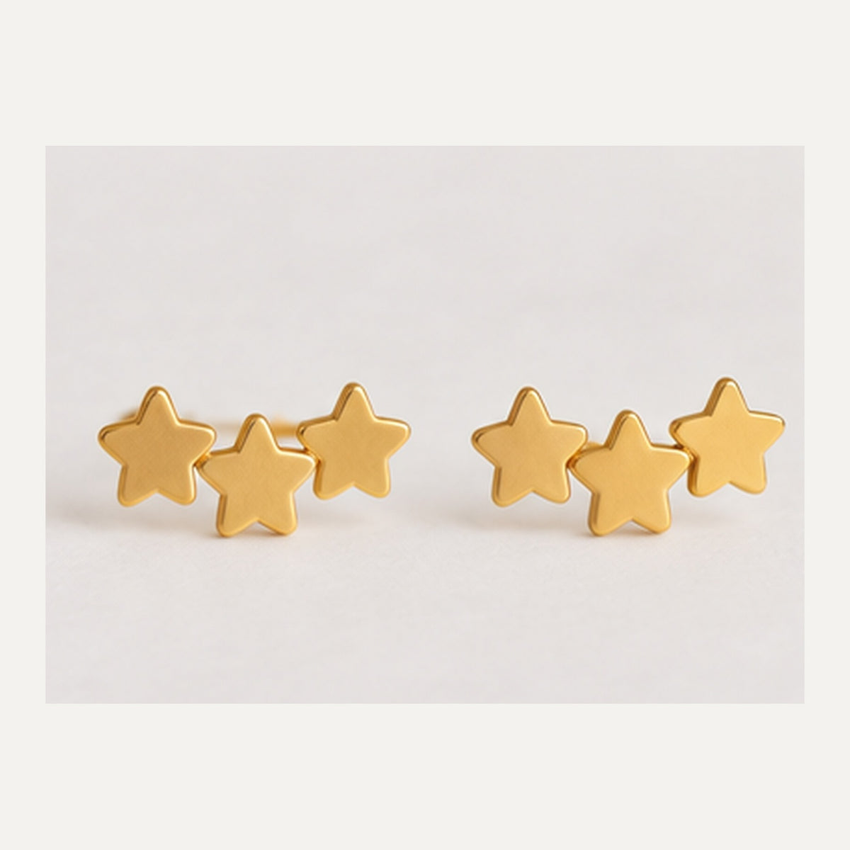 Par de pendientes dorados de tres estrellas en foto profesional