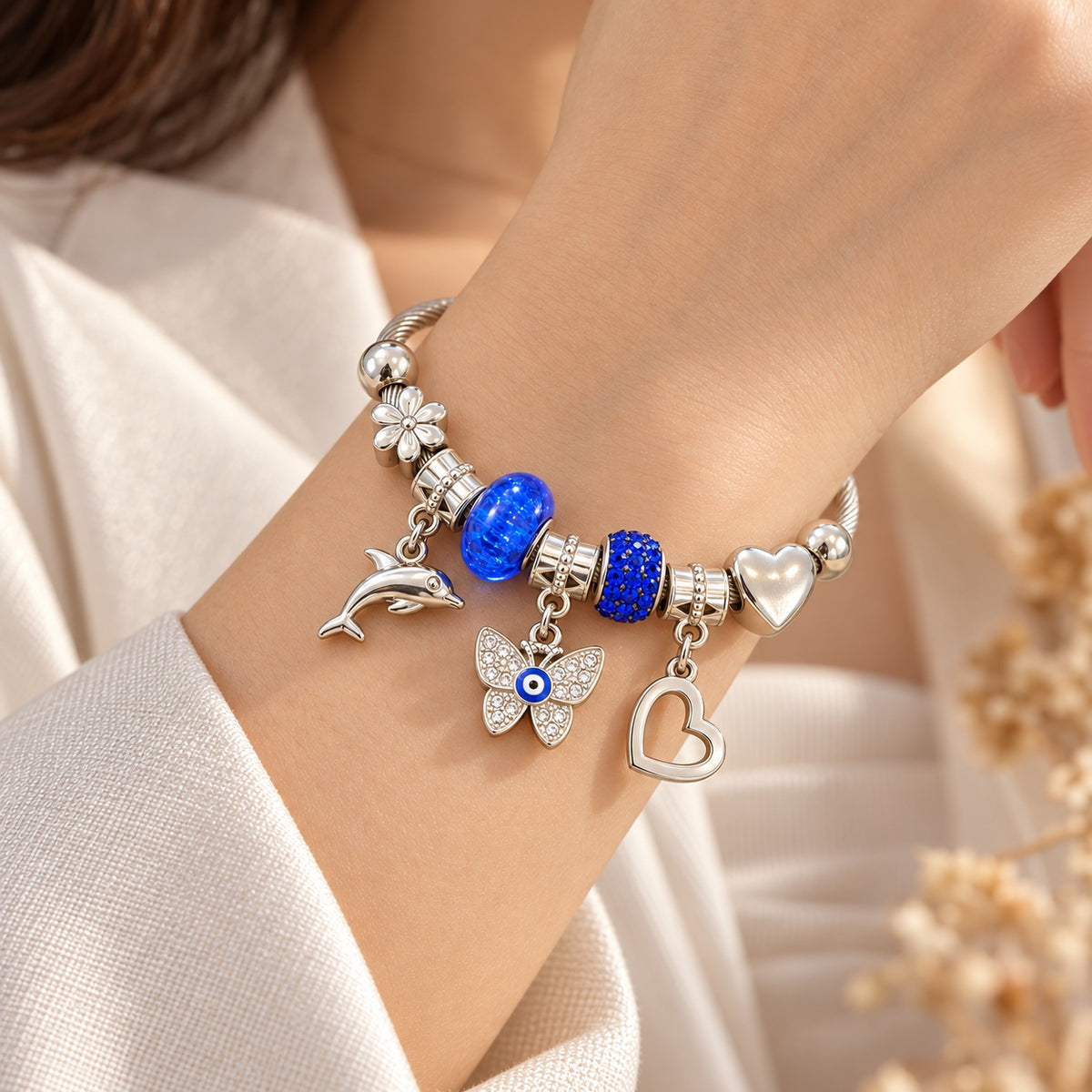 Pulsera azul con delfín mariposa y corazón en muñeca